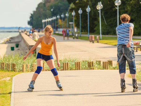 Pareja joven en patines de ruedas montando al aire libre — Foto de Stock