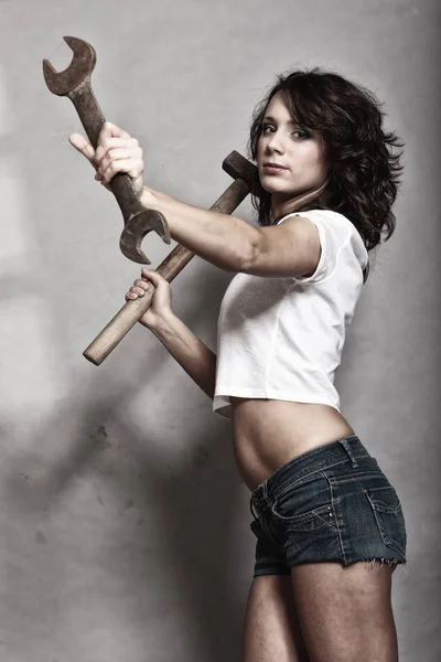 Sexy girl holding hammer and wrench spanner — Stock Photo, Image