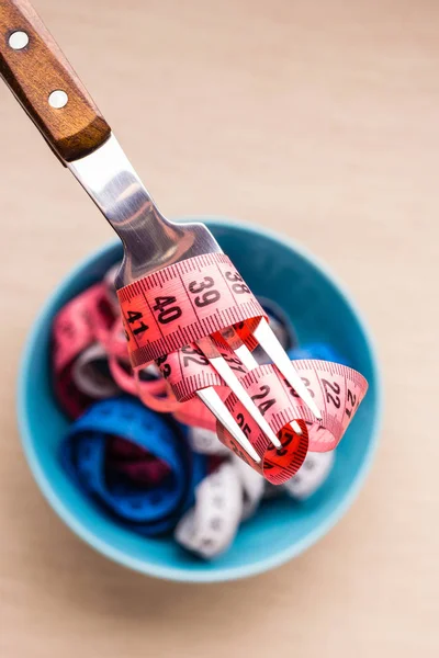 Many colorful measuring tapes in bowl on table — Stock Photo, Image