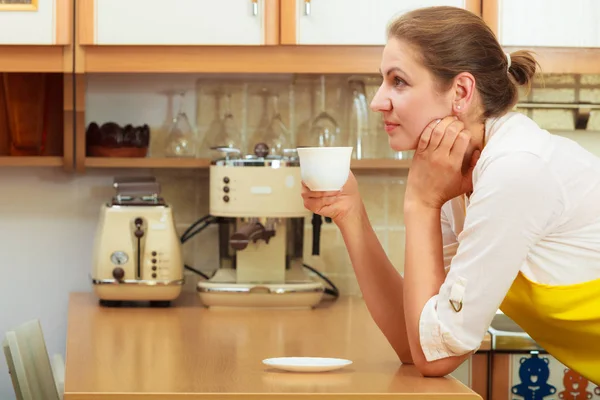 Rijpe vrouw kopje koffie drinken in de keuken. — Stockfoto