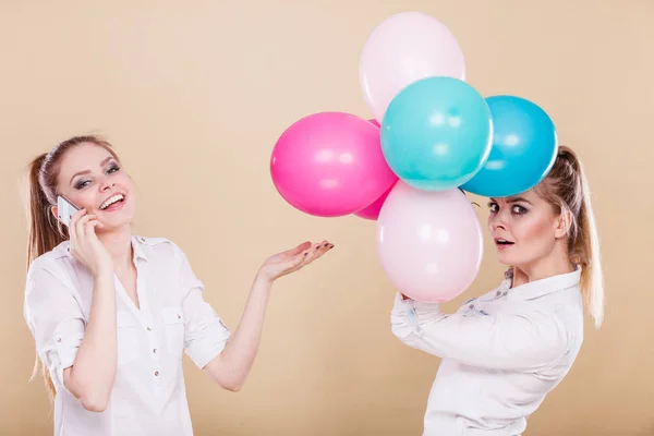 Two girls with mobile phone and balloons