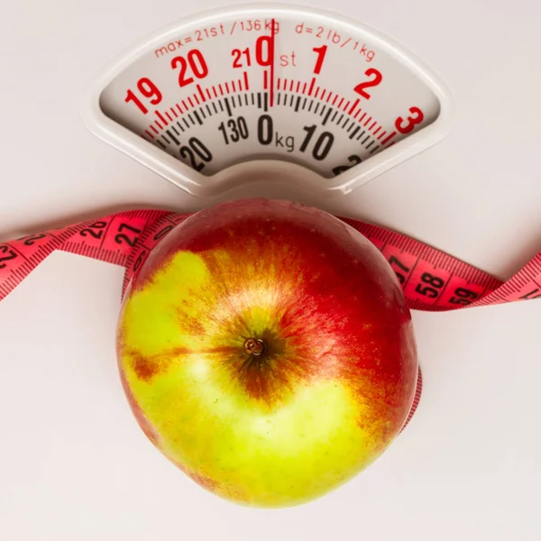 Apple with measuring tape on weight scale. Dieting — Stock Photo, Image
