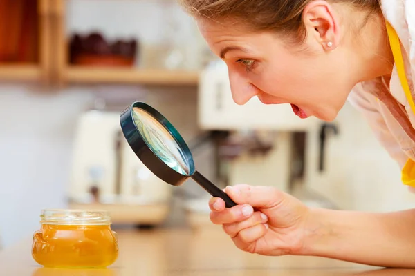 Mulher inspecionando mel com lupa . — Fotografia de Stock