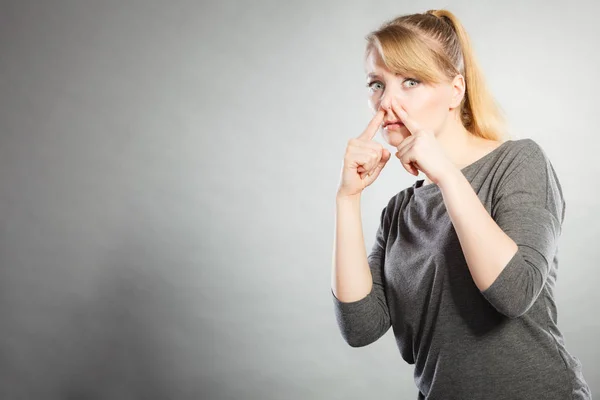 Blonde girl holding nose. — Stock Photo, Image