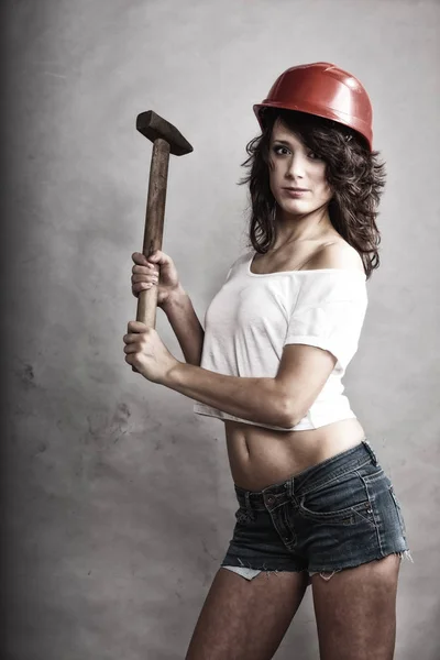 Сексуальна дівчина в безпечному шоломі тримає молоток інструмент — стокове фото