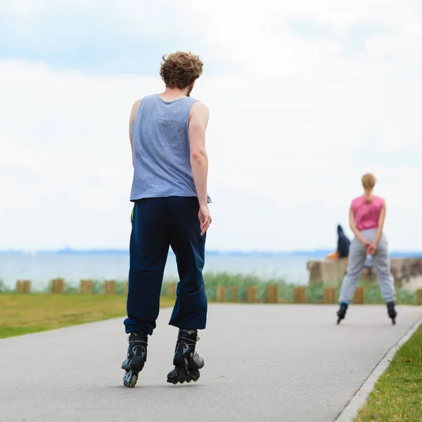 Hombre patinando detrás de la mujer en el paseo marítimo —  Fotos de Stock