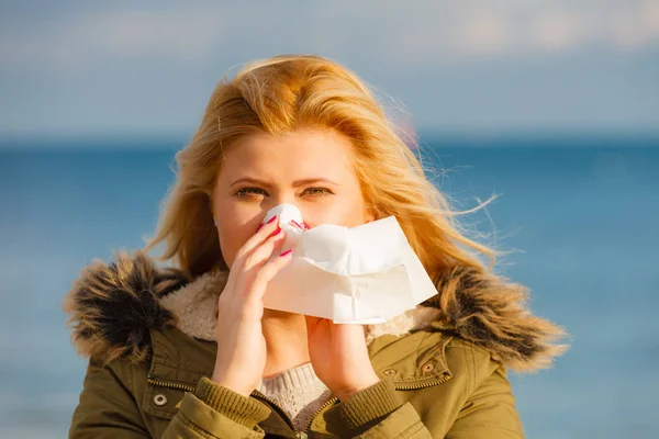 Sneezing woman into handkerchief, outside sunny shot