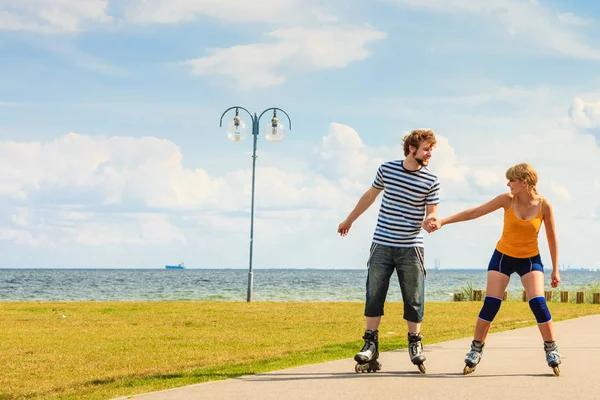 Jovem casal em patins andando ao ar livre — Fotografia de Stock