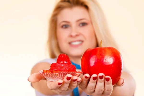 Woman choosing between apple and sweet cupcake — Stock Photo, Image