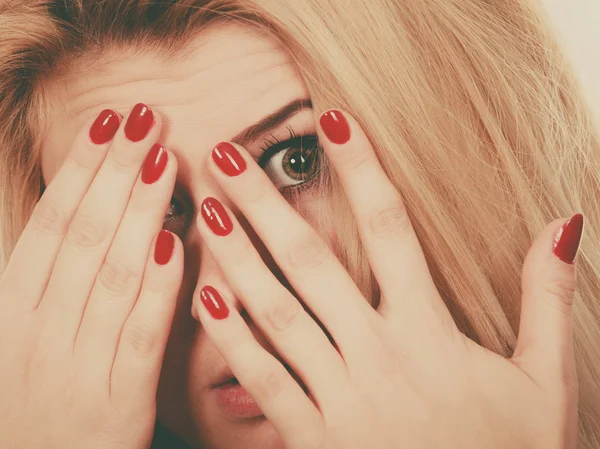 Frau bedeckt Gesicht mit Händen, die rote Nägel zeigen — Stockfoto