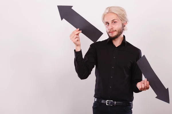 Hombre sosteniendo flechas negras apuntando a izquierda y derecha — Foto de Stock