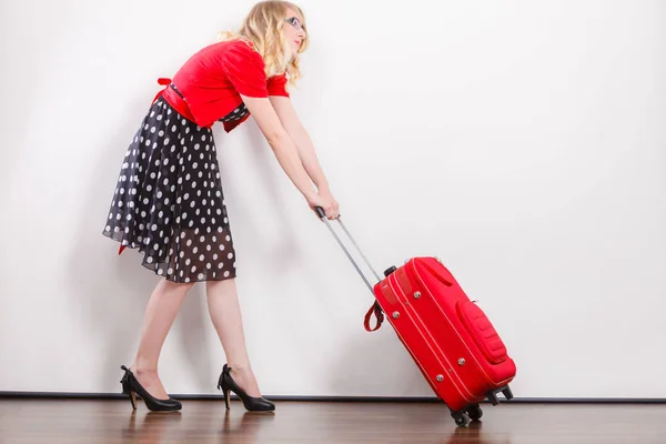 Женщина тянет тяжелый красный дорожный мешок — стоковое фото