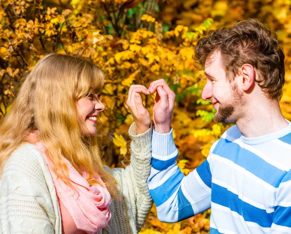Jonge geliefden in herfst park maken hart gebaar. — Stockfoto