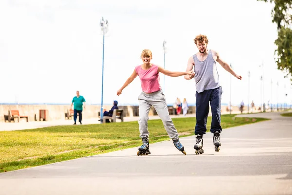 Giovane coppia pattinaggio in parco tenendosi per mano . — Foto Stock