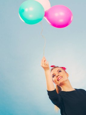 Tatlı gülümseyen kız renkli balonlar tutar.