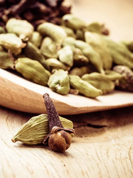 cardamom pods and cloves on wooden spoon