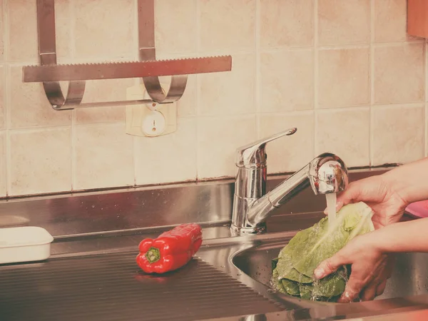 Mujer lavando verduras frescas en la cocina —  Fotos de Stock