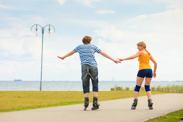 Jovem casal em patins andando ao ar livre — Fotografia de Stock