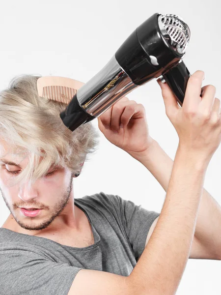 Joven hombre secando el cabello con secador de pelo — Foto de Stock