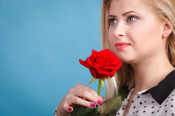 Женщина держит красный цветок розы на голубом — стоковое фото