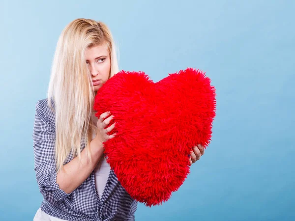 Mujer triste sosteniendo almohada roja en forma de corazón — Foto de Stock