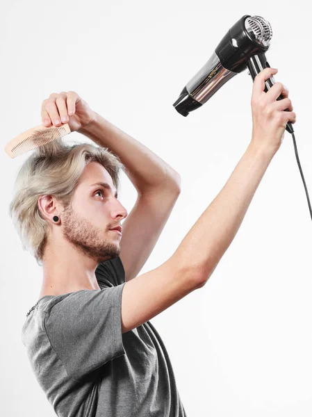 Joven hombre secando el cabello con secador de pelo — Foto de Stock