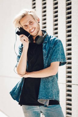 Adam telefon tutarak kulaklık ile gülümseyen hipster