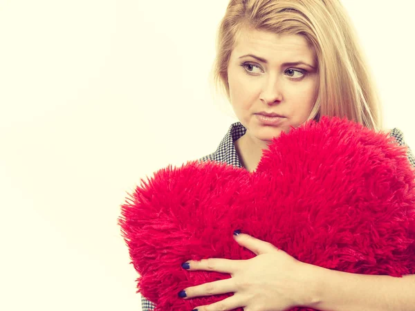 Ragazza triste che tiene grande cuscino rosso a forma di cuore — Foto Stock