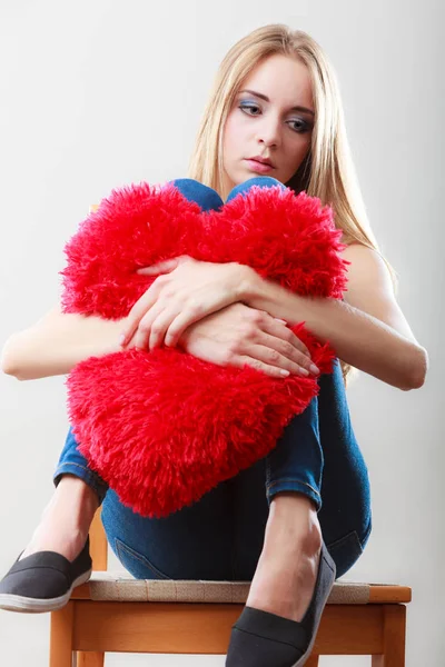 悲伤不快乐的女人，拿着红色的心形枕头 — 图库照片