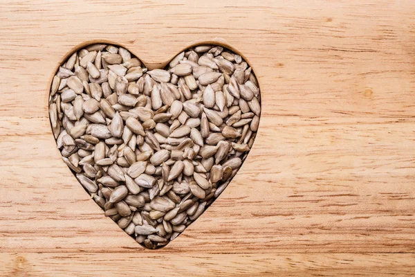 Heart shaped sunflower seeds on wood surface