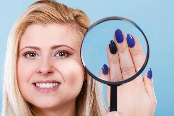 Femme regardant les ongles à travers la loupe — Photo