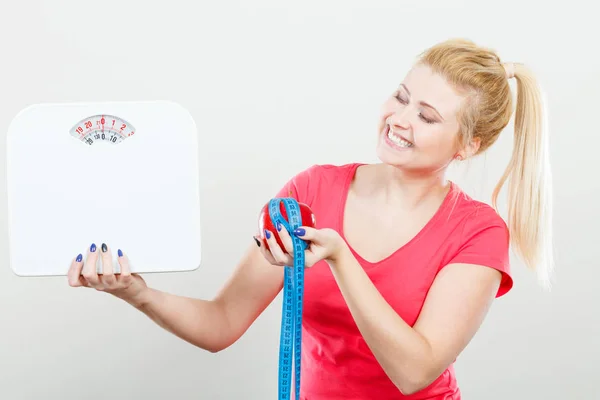 Woman holding apple,measuring tape and weight machine — Stock Photo, Image