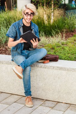 Hipster gülümseyen adam kenarında oturan tablet ile