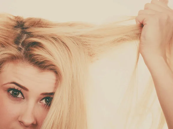 Blonde woman holding her dry hair