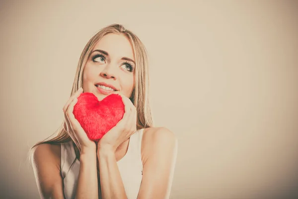 Mujer sonriente sosteniendo el símbolo de amor corazón rojo —  Fotos de Stock