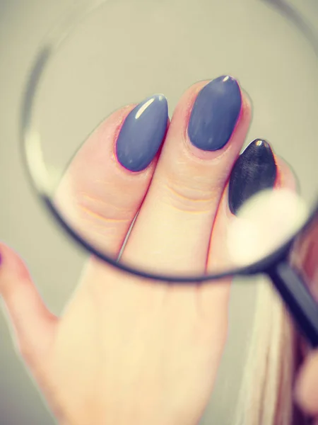 Woman looking at nails through magnifying glass — Stock Photo, Image