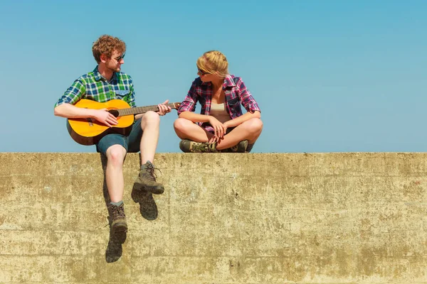 Молодий чоловік грає на гітарі з дівчиною на відкритому повітрі — стокове фото