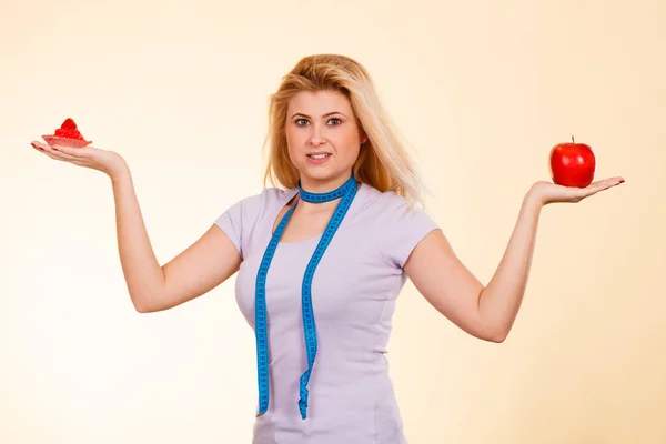 Woman with measuring tape choosing what to eat — Stock Photo, Image