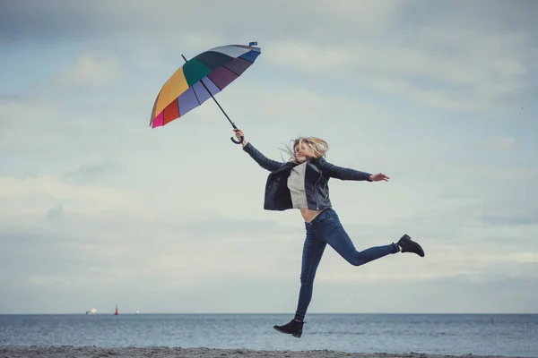 Mujer saltando con paraguas de colores en la playa — Foto de Stock