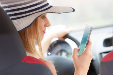 Arabasını kullanırken telefonu kullanan bir kadın.