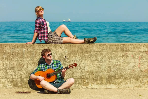 Giovane uomo che suona la chitarra alla sua ragazza dal mare — Foto Stock