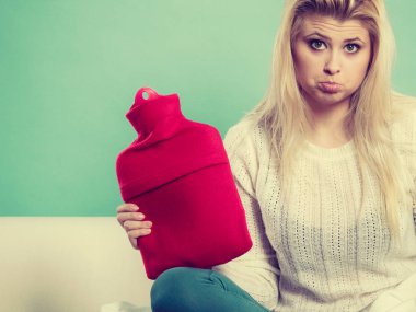 Sıcak su şişesi holding kanepede oturan kadın