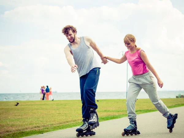 Giovane coppia tenendosi per mano mentre rollerblading — Foto Stock