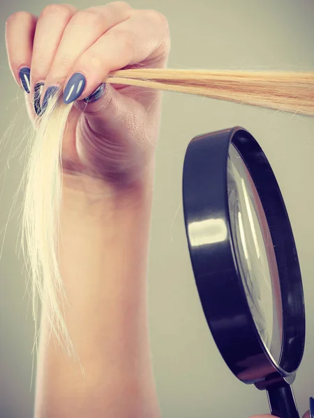 Femme regardant les cheveux à travers la loupe — Photo