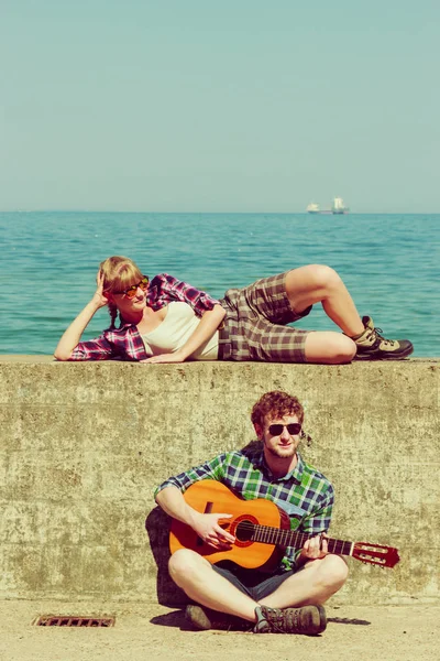 Giovane uomo che suona la chitarra alla sua ragazza dal mare — Foto Stock