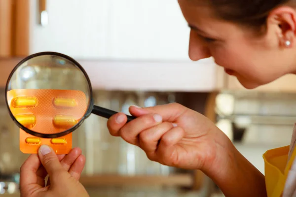 Kvinnan inspektera piller med förstoringsglas. — Stockfoto