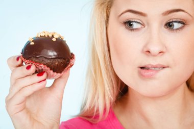 Çikolatalı kek tutan kadın ısırmak üzere.