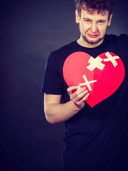 Very sad young man holding broken heart — Stock Photo, Image