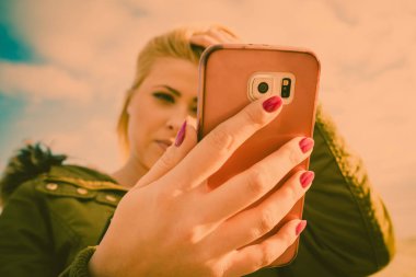 Dışarıda, güneşli bir gün onun smartphone kullanan kadın