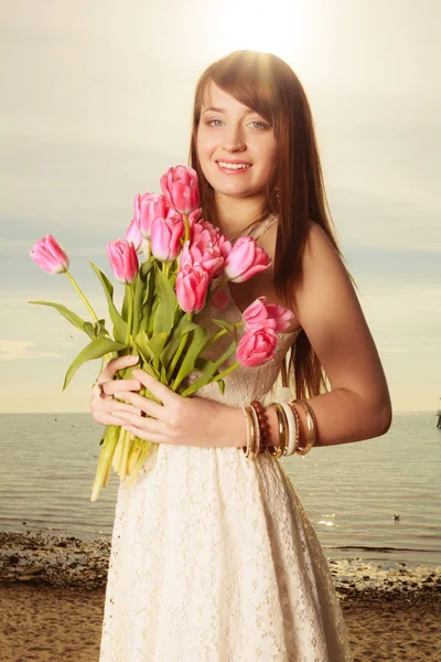 Retrato de mujer sosteniendo flores rosadas en la playa —  Fotos de Stock